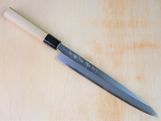 240mm Sirogami No.3 Yanagiba forged by Takahashikusu laying on wooden background with it's cutting edge facing south