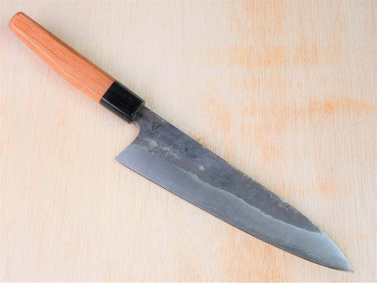 Kurouchi gyuto forged by Asano Fusataro laying on wooden background with it's cutting edge facing south