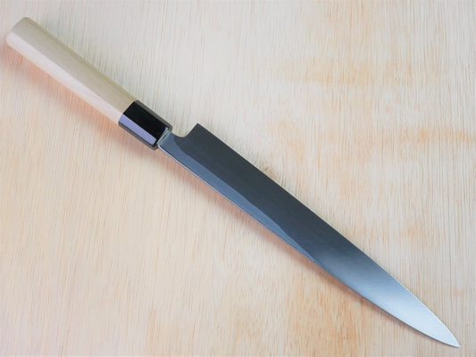 240mm Sirogami No.3 Yanagiba forged by Takahashikusu laying on wooden background with it's cutting edge facing north