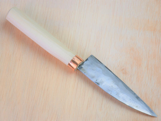130mm Shirogami No.3 Santoku forged by Tsutomu Takahashi laying on wooden background with it's cutting edge facing north