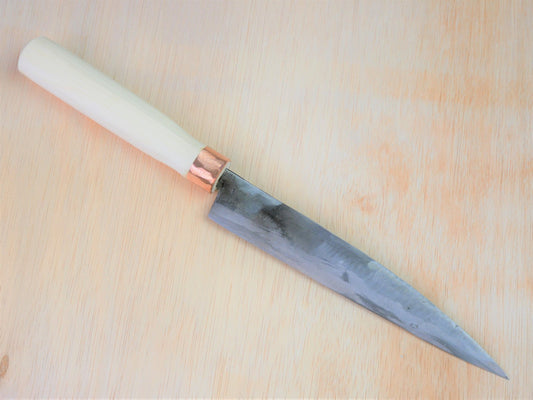 180mm Shirogami No.3 Yanagiba forged by Tsutomu Takahashi laying on wooden background with it's cutting edge facing south