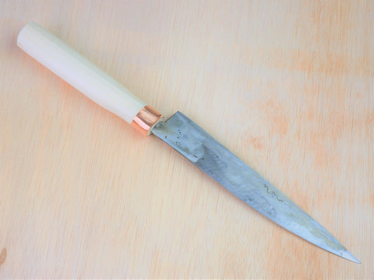 180mm Shirogami No.3 Yanagiba forged by Tsutomu Takahashi laying on wooden background with it's cutting edge facing north