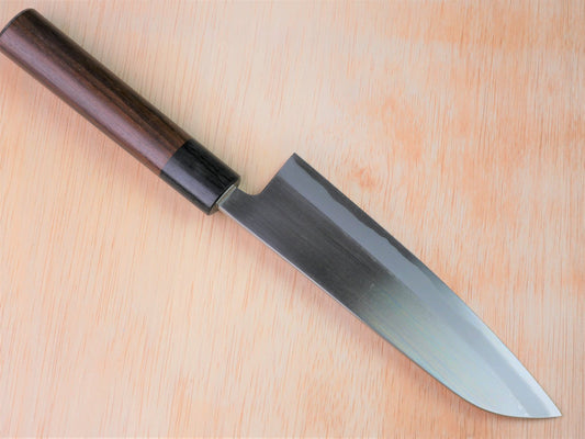 165mm Aogami No.2 special Santoku forged by Yasuaki Taira laying on wooden background with it's cutting edge facing north