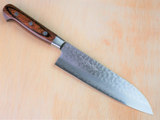 180 mm VG10 hammered Gyuto forged by Yamawaki Hamono laying on wooden background with it's cutting edge facing south