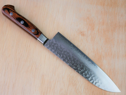180 mm VG10 hammered Gyuto forged by Yamawaki Hamono laying on wooden background with it's cutting edge facing north