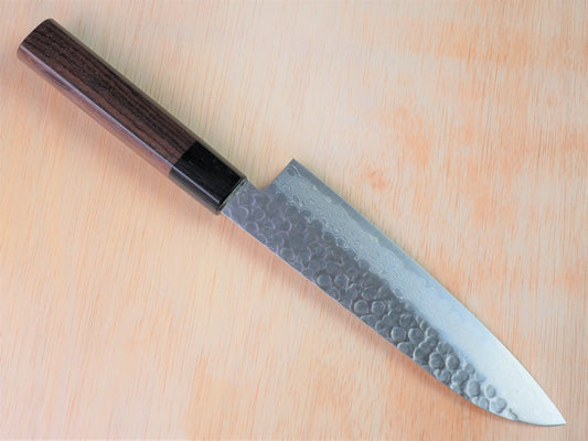 180 mm VG10 hammered Gyuto forged by Yamawaki Hamono laying on wooden background with it's cutting edge facing north