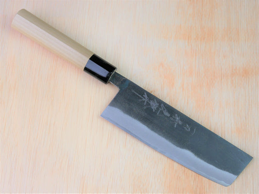 165mm Sirogami No.2 kurouchi Nakiri forged by Takahashikusu laying on wooden background with it's cutting edge facing south