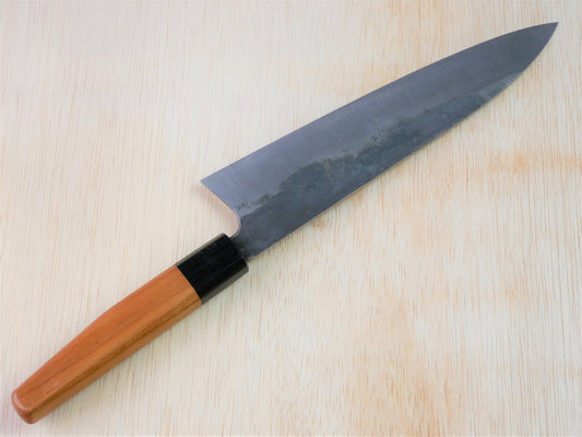 Kurouchi gyuto forged by Asano Fusataro laying on wooden background with it's cutting edge facing north
