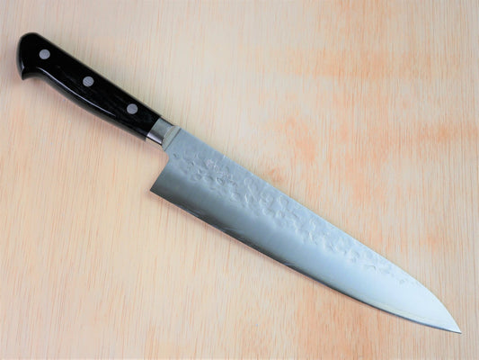 210mm VG10 gyuto forged by Takahashikusu laying on wooden background with it's cutting edge facing south