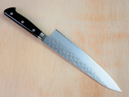 210mm VG10 gyuto forged by Takahashikusu laying on wooden background with it's cutting edge facing north
