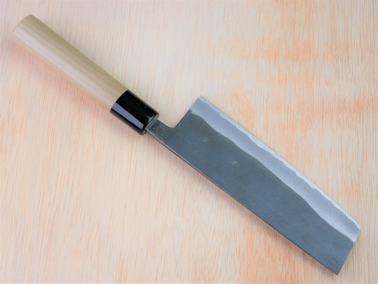165mm Sirogami No.2 kurouchi Nakiri forged by Takahashikusu laying on wooden background with it's cutting edge facing north