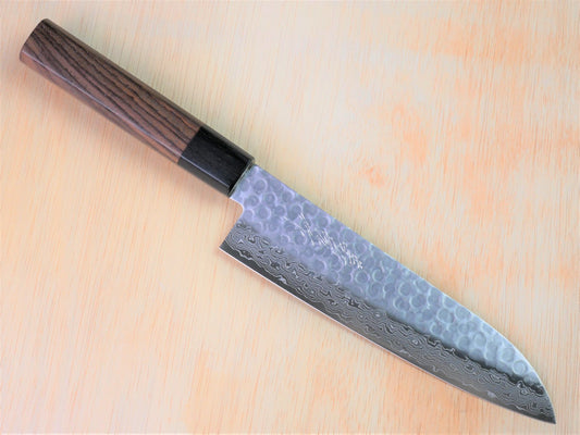 180 mm VG10 hammered Gyuto forged by Yamawaki Hamono laying on wooden background with it's cutting edge facing south