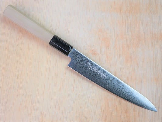 150mm ZA18 damasucus petty forged by Yamawaki Hamono laying on wooden background with it's cutting edge facing south